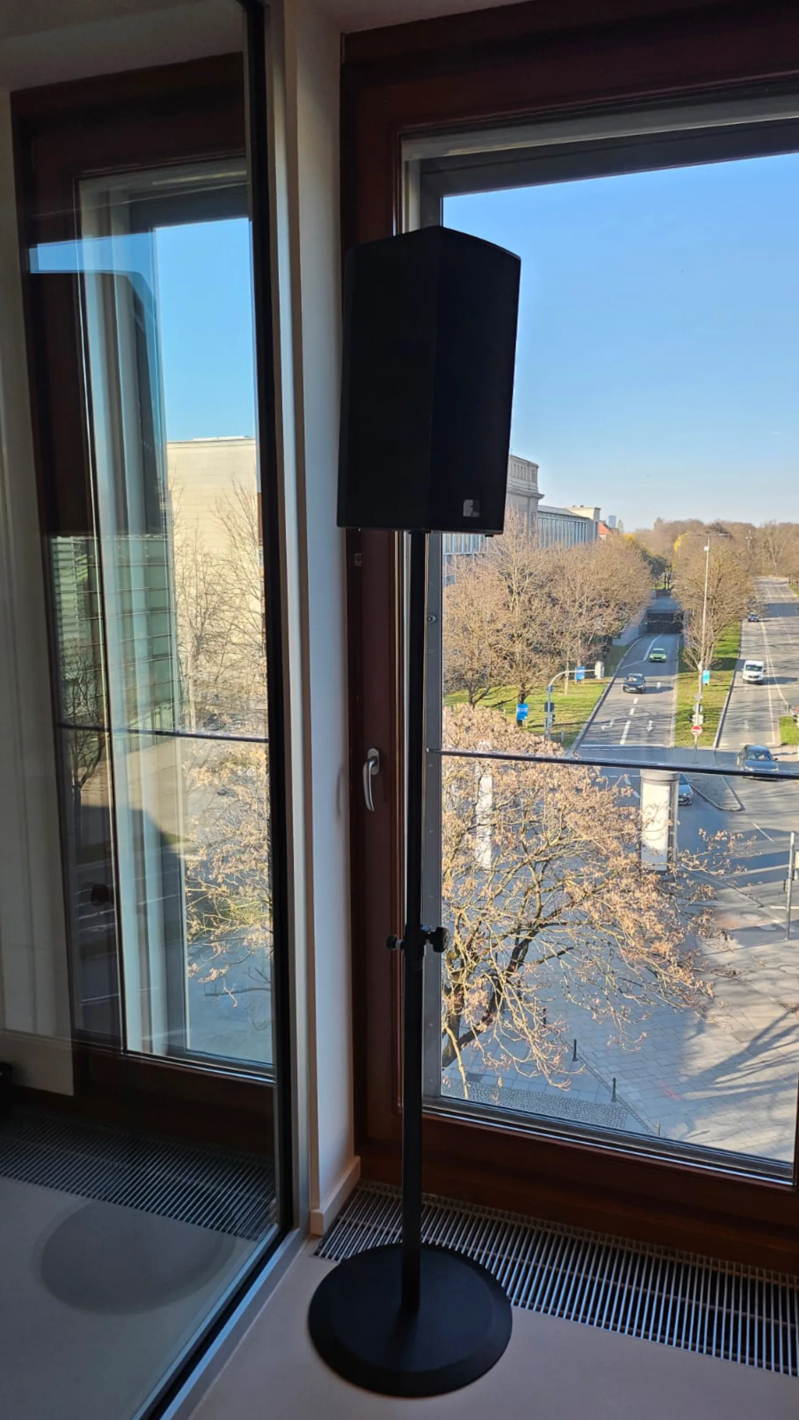 Aktivlautsprecher auf Stativ vor Stadtfenster für Konferenzbeschallung